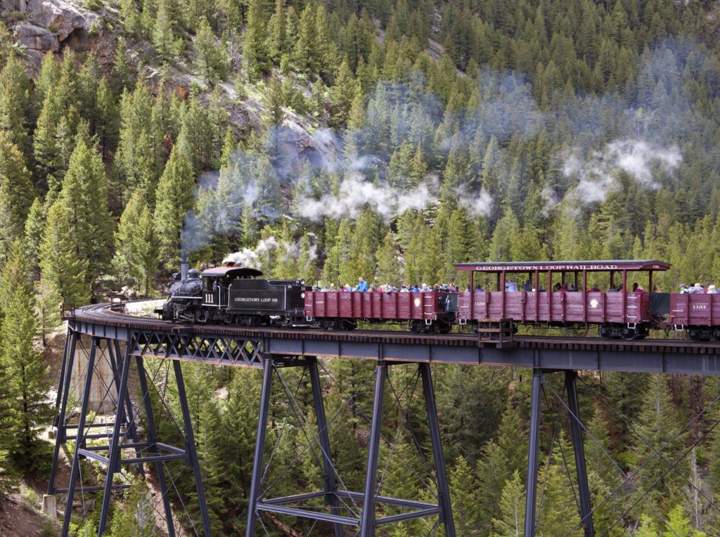 Photo of steam locomotive and train on bridge